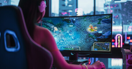 Japanese Female Gamer Playing Online RPG Strategy Video Game on a Computer in a Stylish Futuristic Room. Over the Shoulder Shot of an Asian Woman Battling in eSports Tournament with Other Players © Gorodenkoff