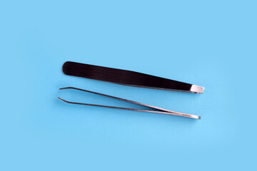Tweezers on blue background. Copy space