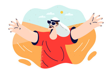 Man in arab sheikh headdress and sunglasses spreads arms out to sides as travels through desert