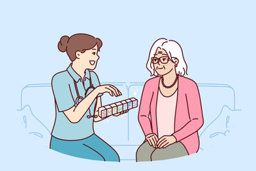 Doctor prescribes medication to elderly female patient and holds pills with smtwtfs letters. Organizer for pills in hands of therapist caring for grandmother suffering from sclerosis