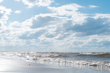 Wonderful view of clean beach seashore coastline, calm blue water, little sea waves, turquoise sky on sunny day. Summer.