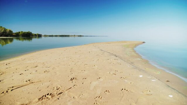 A ledge of sandy river bank with smooth water. Dolly shot