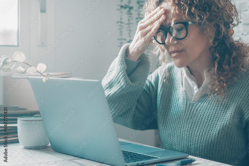 Wall mural young frustrated woman working at office desk in front of laptop suffering from chronic daily headac