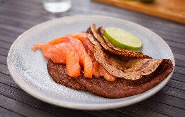 Salted salmon fillet with buckwheat pancakes and lime