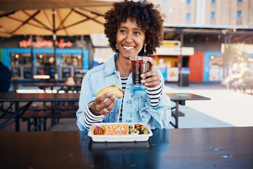 Smiling woman enjoying a drink with some tacos on a restaurant patio