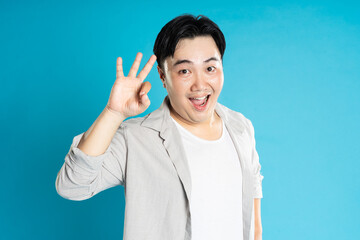 Portrait of an Asian guy posing on a blue background