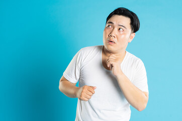 Portrait of an Asian guy posing on a blue background