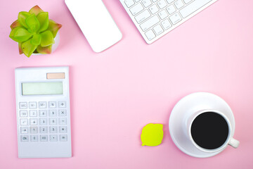 pink office table with computer, pen and a cup of coffee, lot of things. Top view with copy space.