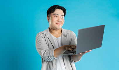 Image of Asian man using laptop on blue background