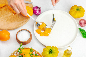 A woman is preparing a tomato salad. Ripe vegetables, herbs, aromatic spices, olive oil
