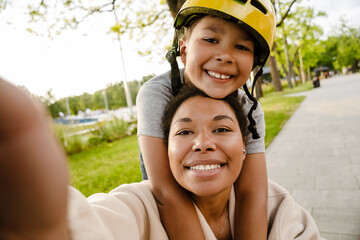 Joyful family mom and son taking selfies while spending time together in park