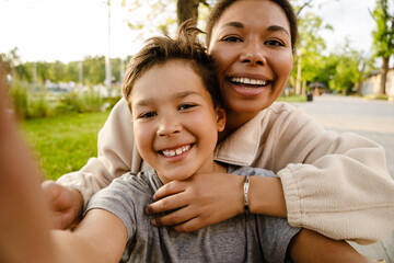 Joyful family mom and son taking selfies while spending time together in park - 646788687