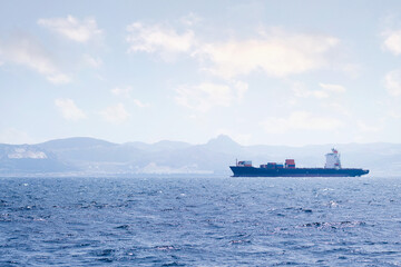 cargo ship sailing by the sea near the coast on a sunny day, concept of maritime transport of goods and import and export trade