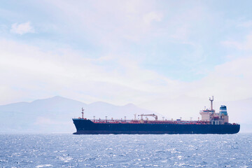 oil tanker ship sailing by the sea near the coast on a sunny day, concept of maritime transport of...