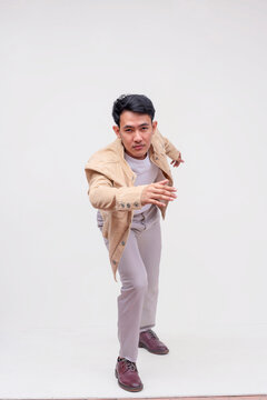 A handsome FIlipino guy in a khaki jacket, white shirt and light gray pants dashing forward towards the camera. Whole body photo, isolated on a white background.