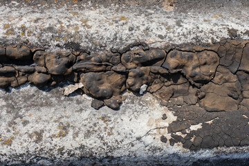 Cracks in the waterproofing of an old roof, cracked black bitumen mastic