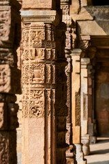 Stone columns with decorative bas relief of Qutb complex in South Delhi, India, close up pillars in ancient ruins of mosque landmark, popular touristic spot in New Delhi, ancient indian architecture