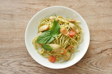 pesto spicy stir fried spaghetti with slice sausage and basil sauce on plate 