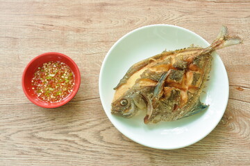 crispy fried black butterfish or silver pomfret arranging on white plate dipping spicy chili sauce in cup