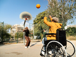 Group of male friends one with a wheelchair playing basketball in a city.Friendship and disability