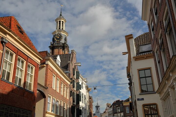Traditional historic medieval houses in the old picturesque town of Zutphen, Gelderland, Netherlands, with the tower Wijndragerstoren (or Wijnhuistoren) in the background 