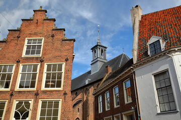 Traditional historic medieval houses in the old picturesque town of Zutphen, Gelderland, Netherlands, with the Broederenkerk church (housing a public library) in the background 