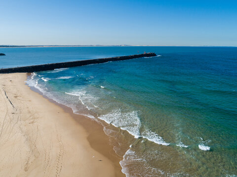 Newcastle breakwater going from beach out into blue ocean