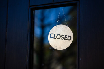 Closed sign hanging in glass pane of shop front door
