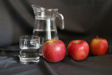 still life, a glass of water and ripe apples, a decanter in the background