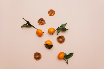 A composition of tangerines and dried candied fruits lie on a beige background. Christmas theme