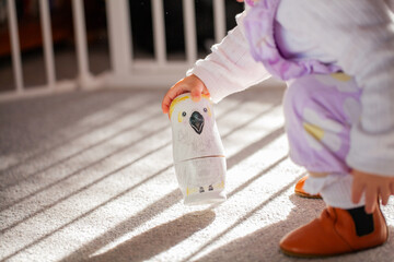 Toddler girl child playing on floor inside home with australian bird babushka nesting dolls