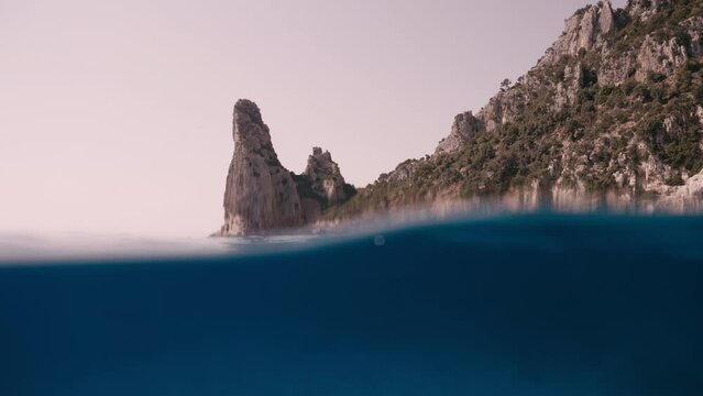 Split shot, camera emerges, half above, half below of emerald sea in Italy, Sardegnaa