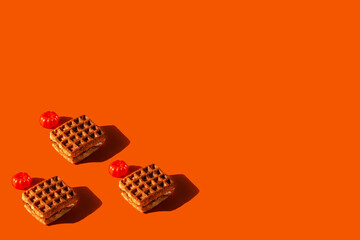 Waffles and pumpkins on an orange background with space for text. Stylish bright concept of autumn holidays. Halloween's celebration mockup