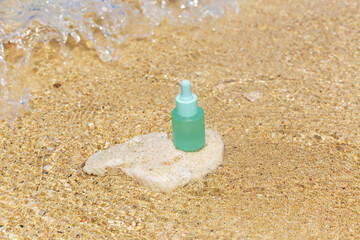 Fototapeta na wymiar Matte serum bottle with pipette on the background of transparent wave and sand