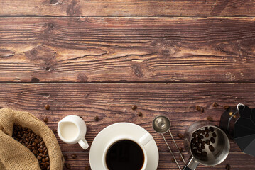 Mark Coffee Day with a captivating top-view photo of roasted coffee beans in a burlap bag, espresso cup on a saucer, jar of cream, coffee turk, barista's measuring spoon, kettle on a wooden backdrop