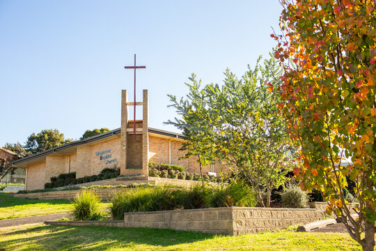 Christian church building with bright autumn colours on tree and wattle bush