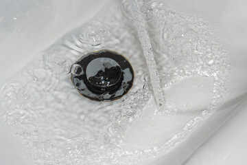 Close-up of sink drain with water and bubbles. A clean and hygienic image for cleaning and sanitation related projects.
