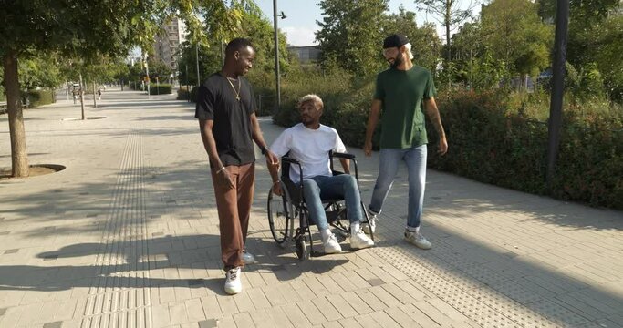 Group of young diverse male friends walking through a city, one of them in a wheelchair. Friendship and disability