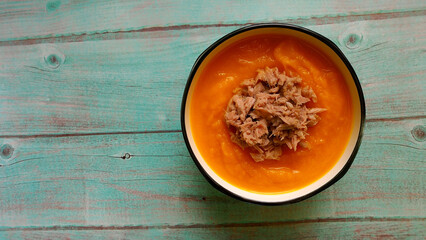 on a blue wooden table, a plate with pumpkin cream soup C. top view. diet. gluten-free