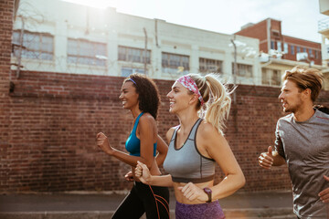Young and diverse group of friends jogging and running together in the city