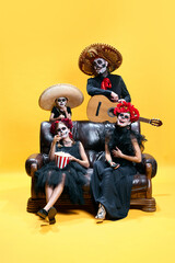 Halloween Family. Happy, laughing father, mother and children in halloween skeleton spooky makeup watching films with pop corn.