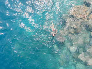 Young woman swimming in blue sea. Aerial top view. Coral reefs in Karimun Jawa, Jepara, Indonesia.