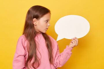 Area for promotional content. Clear spot for marketing. Shocked scared little kid girl wearing pink sweatshirt isolated over yellow background looking with big eyes at empty speech bubble