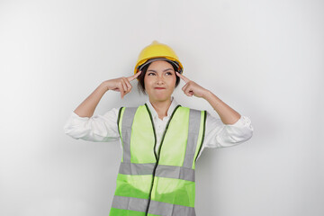 A thoughtful young woman labor worker wearing safety helmet and vest is looking aside to an idea on copy space , isolated by white background. Labor's day concept.