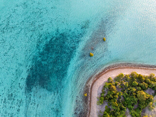 High angle aerial bird's eye drone view of a small beach section of Haman Island, a holiday resort islet with shallow, turquoise water - Whitsunday Islands, Great Barrier Reef, Queensland, Australia.