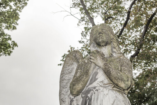 Creepy antique statue with one wing in a cemetery