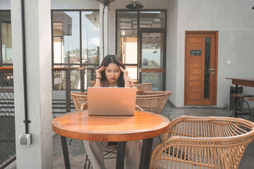 A portrait of Asian business woman looks stressed and depressed while working from coffeeshop