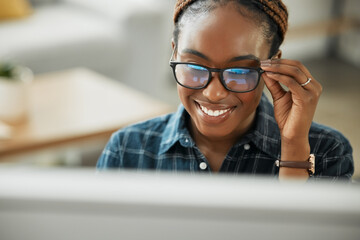 Face, smile and computer with a black woman in glasses working closeup in her home for remote employment. Happy, website and desktop with a young employee at work on her small business startup