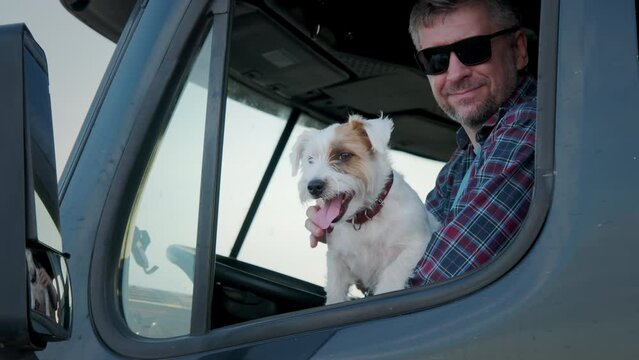 A man trucker sit in a semi truck along with the dog. Close up shot