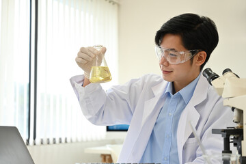 Portrait of a young Asian professional scientist doing an experiment in a lab.